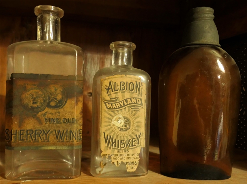 3 Flask Bottles - "Sherry Wine" With Original Labe, "Albion Maryland Whiskey" with Original Label, and Amber "Newmans Baker Bros & Co" Flask with Metal Shot Glass Lid Pat. 1876 - Measures 8" Tall 