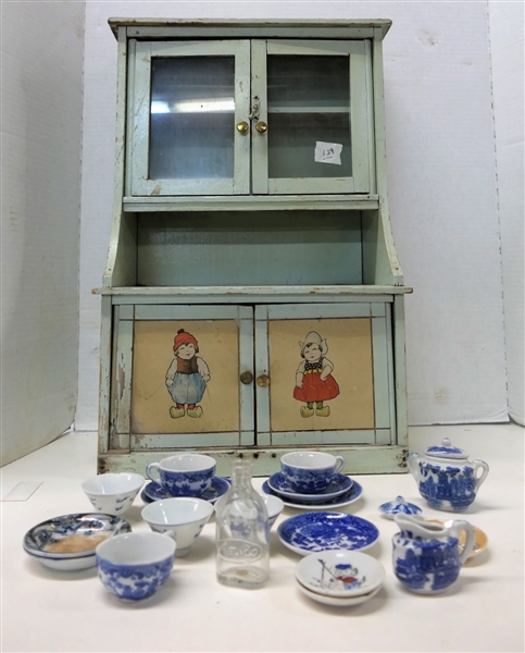 Green Painted Miniature Kitchen Cabinet With Dutch Boy and Girl, Childs Blue Willow Tea Set Pieces, and  Toy Baby Bottle by Amsco- Cabinet Measures Height 19 Inches Base Width 7Inches