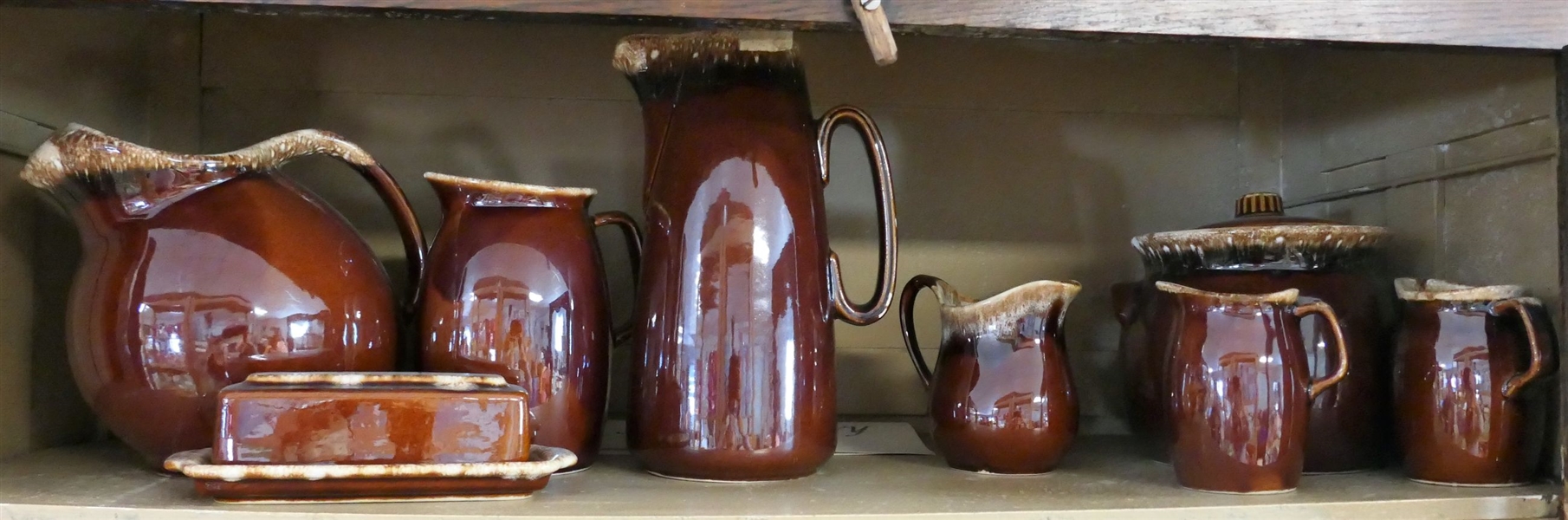 8 Pieces of Brown Hull Pottery including Pitchers, Bean Pot, Butter Dish, and Creamers - Largest Pitcher Measures 10" Tall 