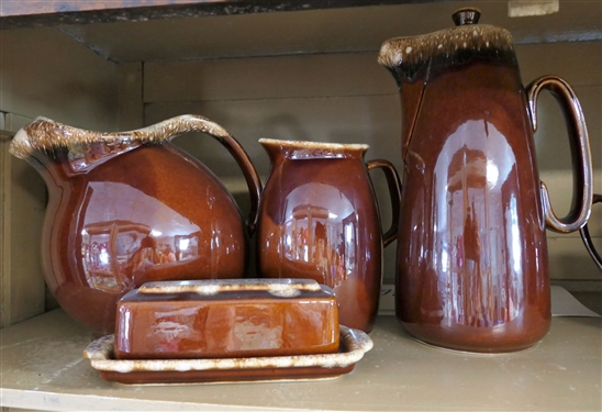 8 Pieces of Brown Hull Pottery including Pitchers, Bean Pot, Butter Dish, and Creamers - Largest Pitcher Measures 10 Tall 