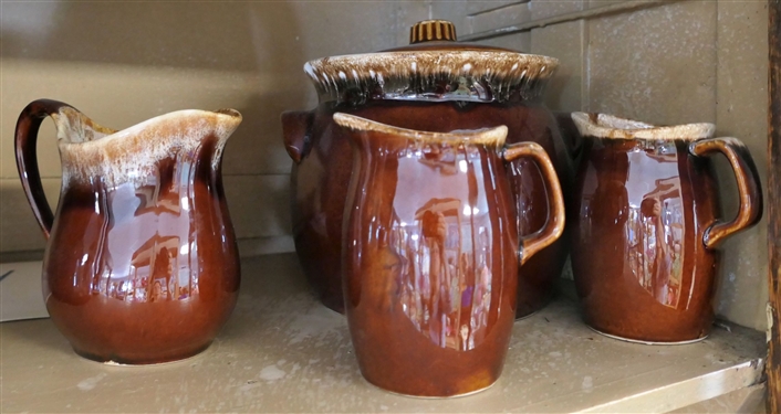 8 Pieces of Brown Hull Pottery including Pitchers, Bean Pot, Butter Dish, and Creamers - Largest Pitcher Measures 10 Tall 