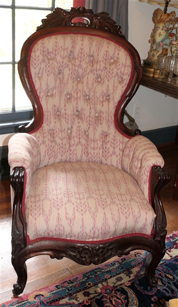Ornately Carved Rosewood Parlor Chair - Carved Crest At Top - Tan and Rose Colored Patterned Upholstery - Measures 43" tall 25" by 22" 