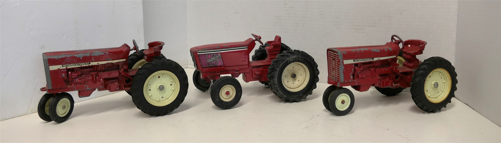 3 Die Cast Tractors - 2 Red International Tractors and ERTL Red Die Cast Metal Tractor  -With Motor Decals - Measuring 4 1/2" Tall 8" Long