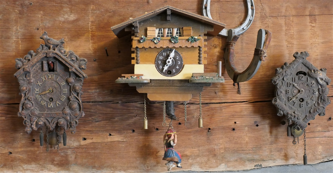 3 Smaller Cuckoo Clocks - Center Germany House Style Clock with Swinging Girl Pendulum -Clock with Left Is Missing 1 Hand  -Center House Clock Measures 5 1/2" Tall 6 1/4" Across -  Horse Shoe Hook...