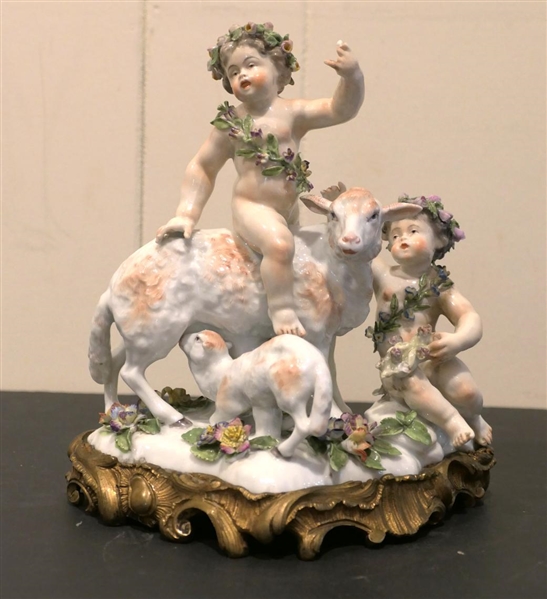 German Porcelain Lamb and Putti Figure - Delicate Porcelain Flowers on Base, and Crowns -Ornate Metal Base - Figure is 8" Tall 8" Across - Few Small Broken Petals, Fingers on Putti are Broken 