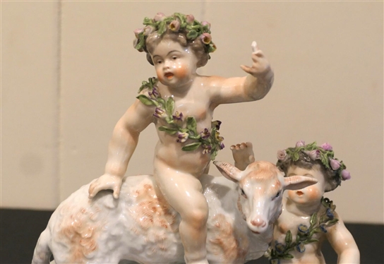 German Porcelain Lamb and Putti Figure - Delicate Porcelain Flowers on Base, and Crowns -Ornate Metal Base - Figure is 8 Tall 8 Across - Few Small Broken Petals, Fingers on Putti are Broken 